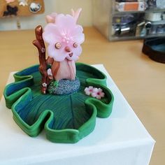 a small figurine is sitting on top of a green leafy planter