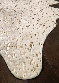 a white rug with gold spots on it sitting on a wooden floor in front of a window