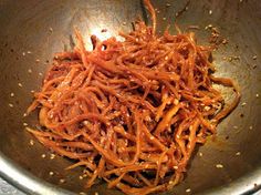 shredded carrots in a metal bowl on top of a table