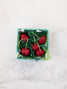 four radishes and greens in a blue container on a white marble countertop