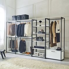 an organized closet with clothes, shoes and bags on shelving units in a white room