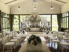 an indoor wedding venue with white chairs and floral arrangements