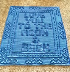 a blue crocheted rug with the words love is in the air on it