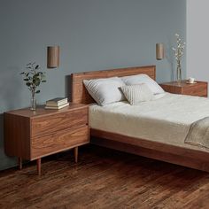 a bed sitting on top of a wooden floor next to a night stand and nightstand