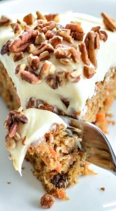 a piece of carrot cake with white frosting and pecans on top