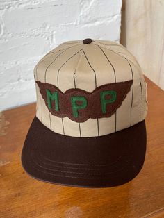 This is a vintage made is USA trucker style hat that I added vintage patches to! Wool 'MPP' patch from the 1940s, and an embroidered 'Mike' workwear name patch. One of a kind. Brown and tan with stripes. In deadstock condition. Adjustable snapback, one size fits most. Gender neutral. All sales are final, so please refer to photos and description. Vintage One Size Fits Most Baseball Cap, Vintage Brown Baseball Cap One Size Fits Most, Retro Beige Baseball Cap With Curved Brim, Retro Brown Trucker Hat With Curved Brim, Vintage Hats With Embroidered Logo, Vintage Hat With Embroidered Logo And Curved Brim, Vintage Hats With Embroidered Logo And Curved Brim, Retro Baseball Cap With Letter Patch, Retro Flat Bill Hat With Logo Patch