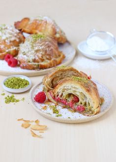 two plates with pastries and raspberries on them