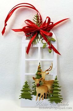 a christmas ornament hanging from the side of a window with a red bow on it