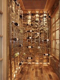 a wine cellar with lots of bottles on the wall and wooden flooring in front of it