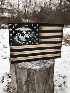 an american flag made out of wood sitting on top of a tree stump in the snow