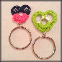 two heart shaped keychains are shown on a white surface, one is green and the other is pink