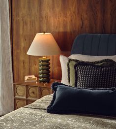 a bed with two pillows and a lamp on the side table in front of it