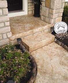 a house with stone steps leading up to the front door and flowers growing on the side