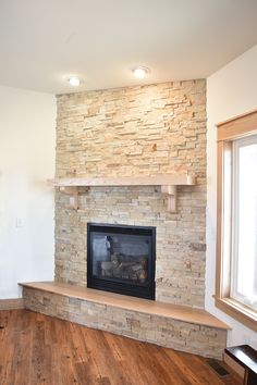 an empty living room with a fireplace and wood floor