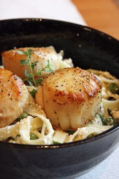 some scallops and noodles in a black bowl