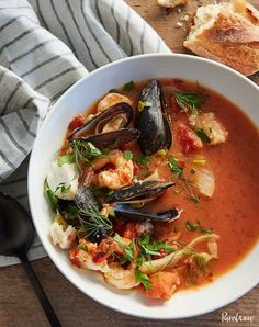 a bowl of seafood soup with bread on the side