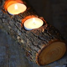 three lit candles sitting on top of a piece of wood