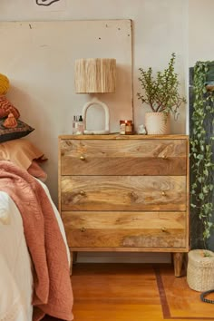 a bedroom with a bed, dresser and plants on the nightstands next to it