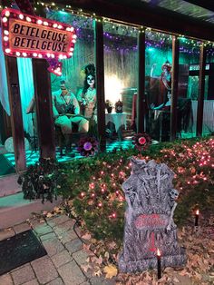 a halloween display in front of a building with lights on the windows and decorations around it