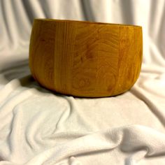 a wooden bowl sitting on top of a white sheet