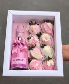 a pink box filled with chocolate covered strawberries next to a bottle of wine in it