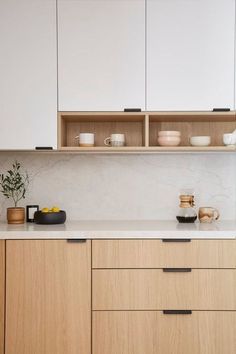 a kitchen with white cabinets and wooden drawers