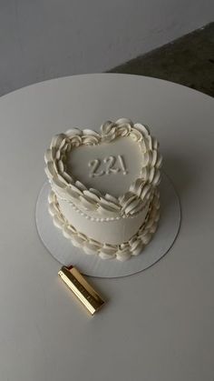 a heart shaped cake sitting on top of a white table next to a gold piece