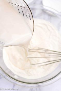 a whisk being poured into a blender filled with cream