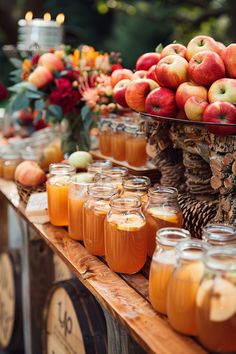 apples and oranges are on display in mason jars at an outdoor wedding reception table