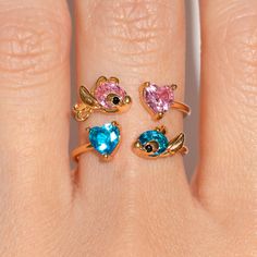 a woman's hand with three rings on it and two different colored stones in the middle