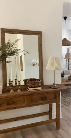 a wooden table topped with a mirror next to a lamp