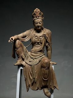 an old statue sitting on top of a white pedestal next to a gray wall and floor