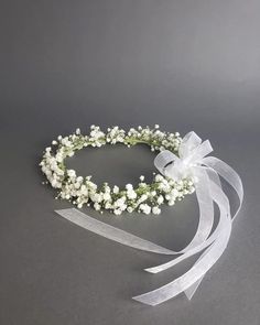 a white headband with baby's breath flowers and ribbons on it, sitting on a gray surface