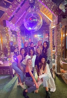 a group of women posing for a photo in front of a disco ball