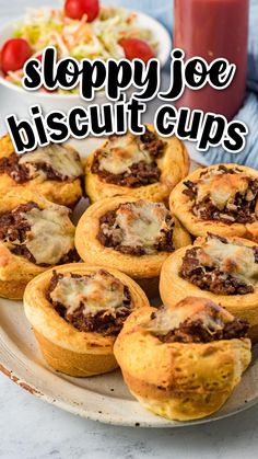 a plate full of sloppy joe biscuit cups on a table with a bowl of salad in the background