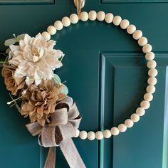 a wreath on the front door with flowers and pearls hanging from it's side