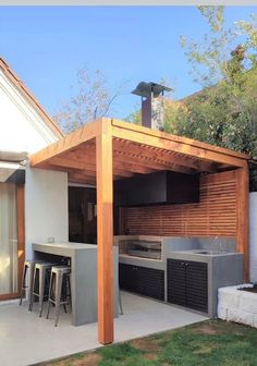 an outdoor kitchen and bar area in a backyard with wood slats on the roof