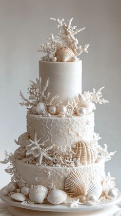 a three tiered wedding cake with seashells on it