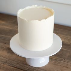 a white frosted cake sitting on top of a wooden table