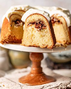 a bundt cake with white frosting and pecans on top is cut in half