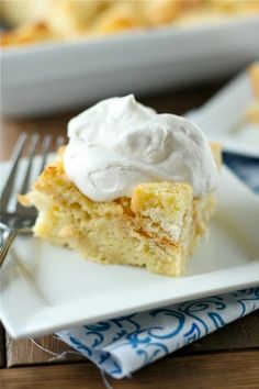 a piece of cake with whipped cream on top is sitting on a plate next to a fork