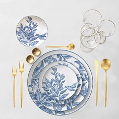 an arrangement of blue and white plates with gold cutlery