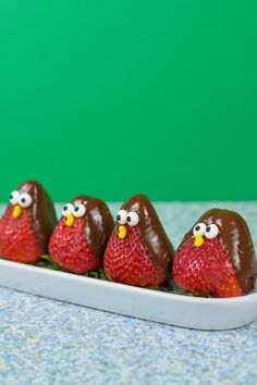 four chocolate covered strawberries with eyes and nose on them sitting in a white tray