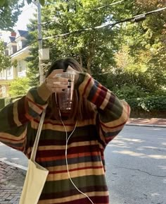 a woman is standing on the street and listening to music