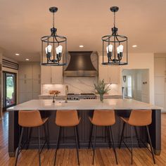 a large kitchen with an island and three pendant lights hanging from it's ceiling