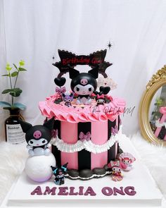 there is a pink and black cake with decorations on it, along with other items