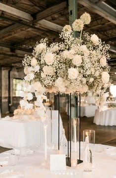 a centerpiece with white flowers and candles sits on a table at a wedding reception