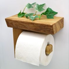 a wooden shelf holding two rolls of toilet paper and a plant on top of it