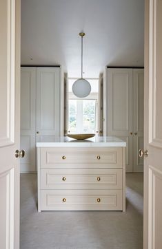 an empty kitchen with white cabinets and a gold bowl on the island