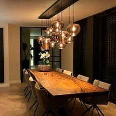 a large wooden table surrounded by chairs and lights